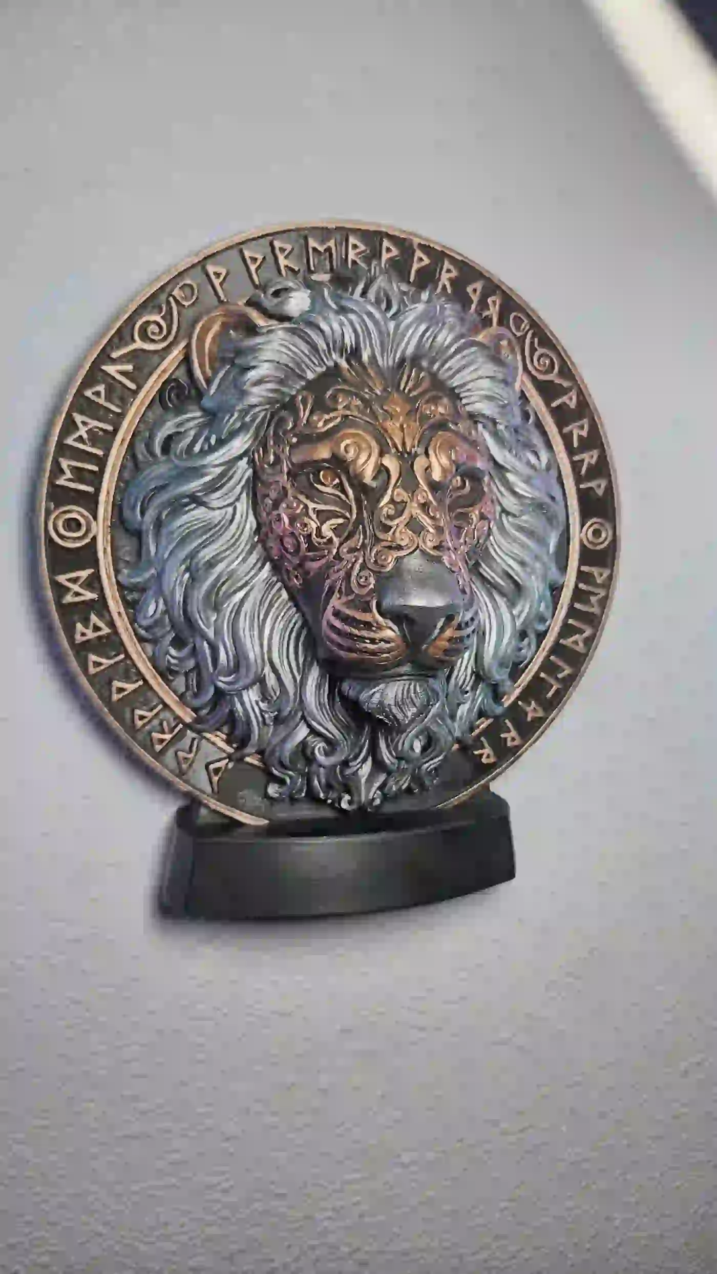 Finished painted lion medallion displayed on a black stand